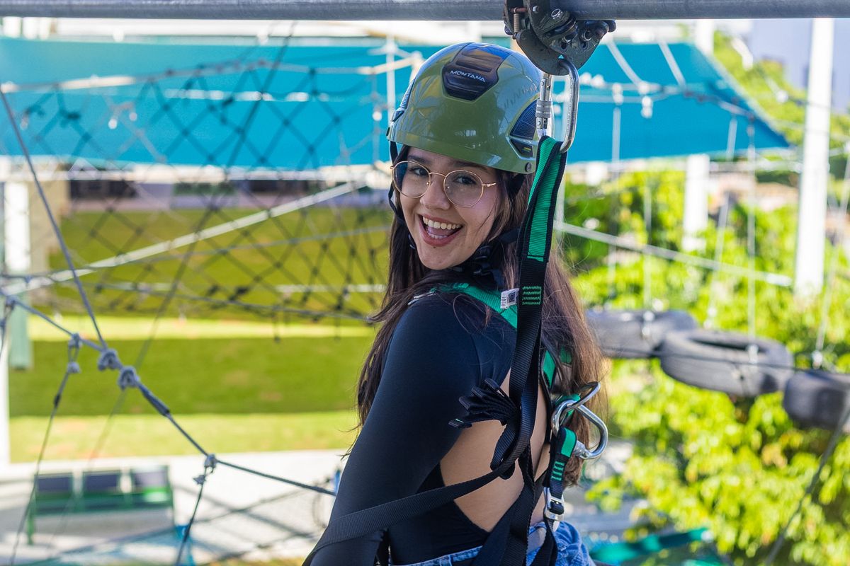 Visitante sorrindo presa à linha de segurança do Arvorismo Tático